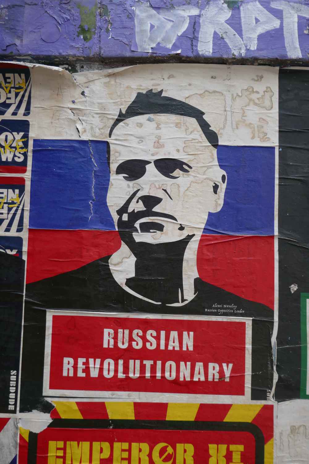 Street art featuring a black and white rendering of Alexei Navalny in front of a Russian flag and with the words 