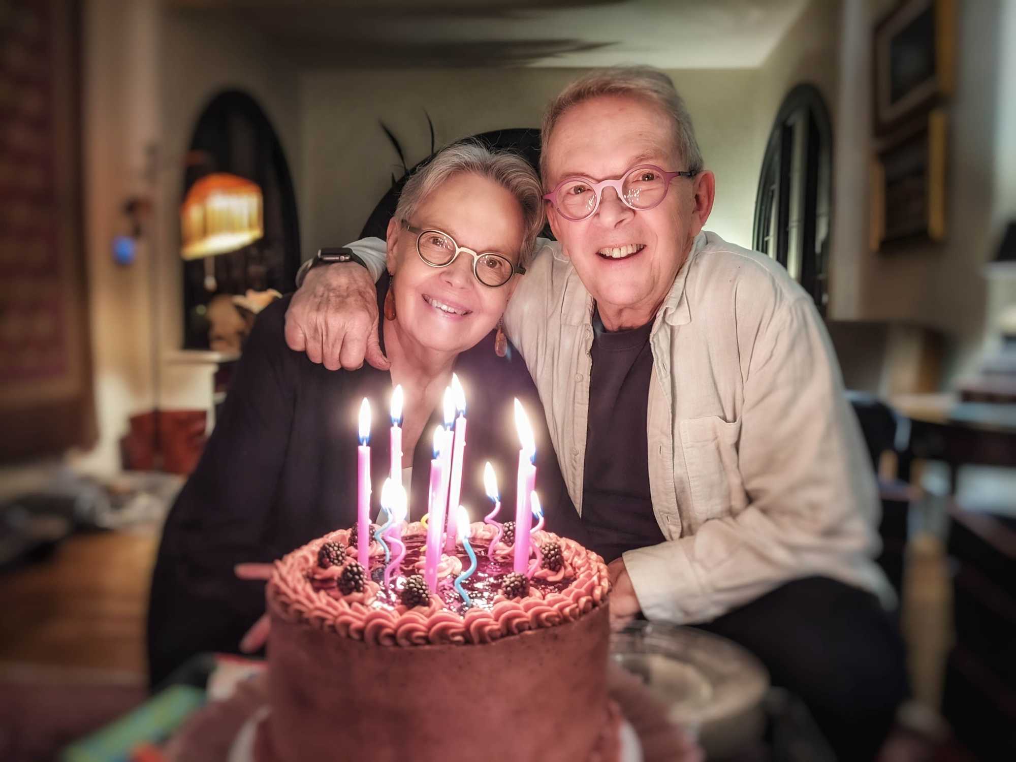 Morris Eaves with his arm around wife Georgia and a birthday cake in the foreground.