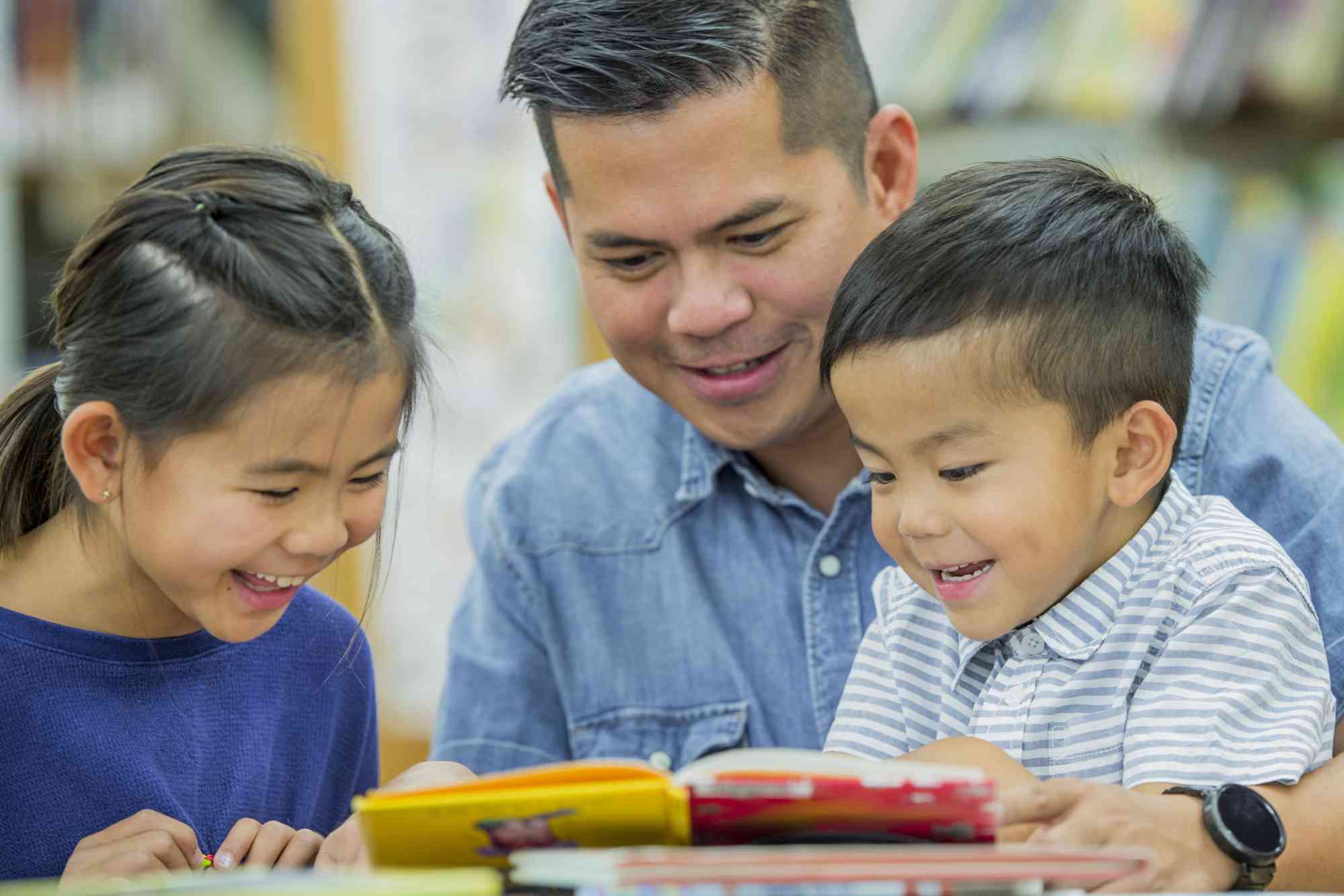 Close-up of a father reading to his son and daughter.