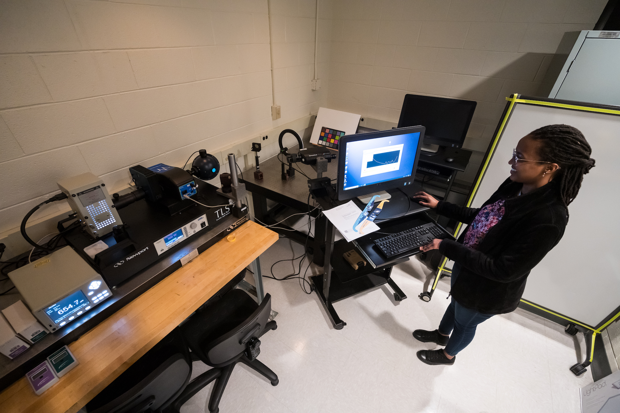 PhD student stands at computer station running a test on a pair of eclipse glasses