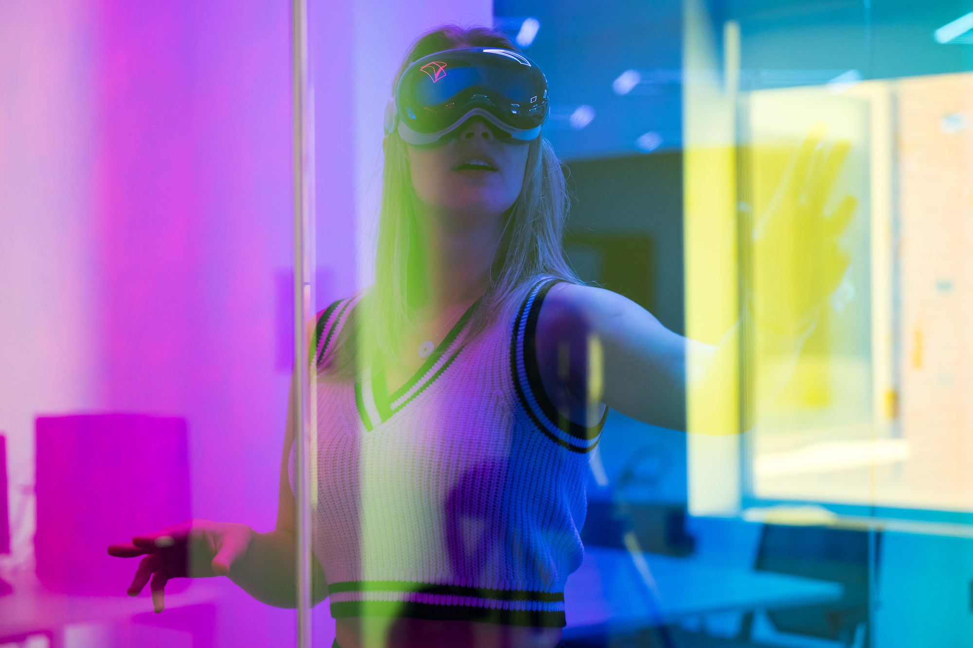 Student wears virtual reality glasses, filtered through a rainbow prism