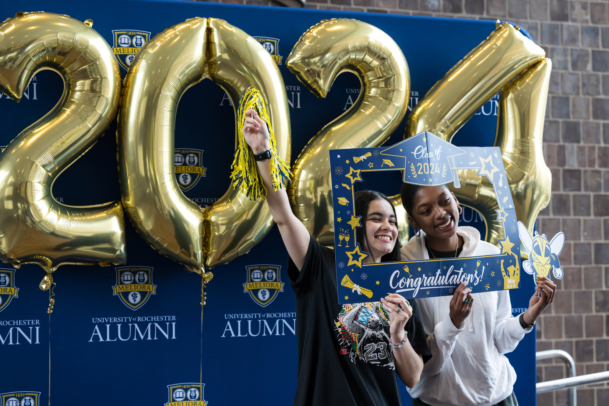 Students stand in front of gold 2024 balloons holding a congratulations sign