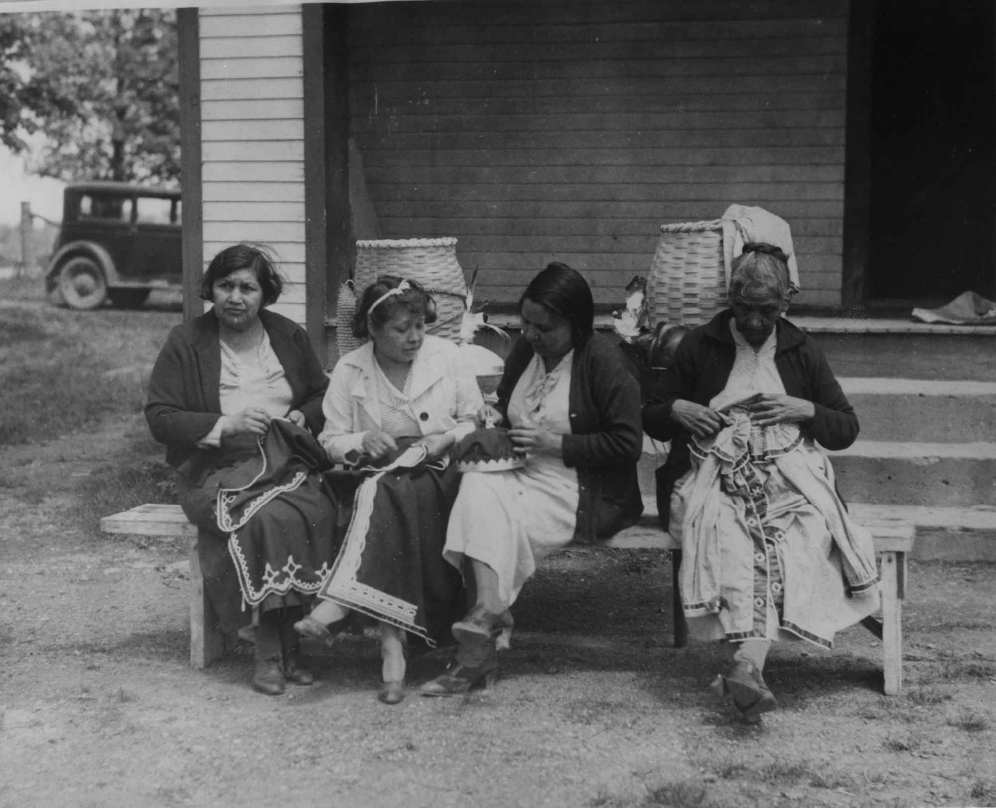 Archival photo of four seated Seneca women creating replicas of their ancestral Native American art.