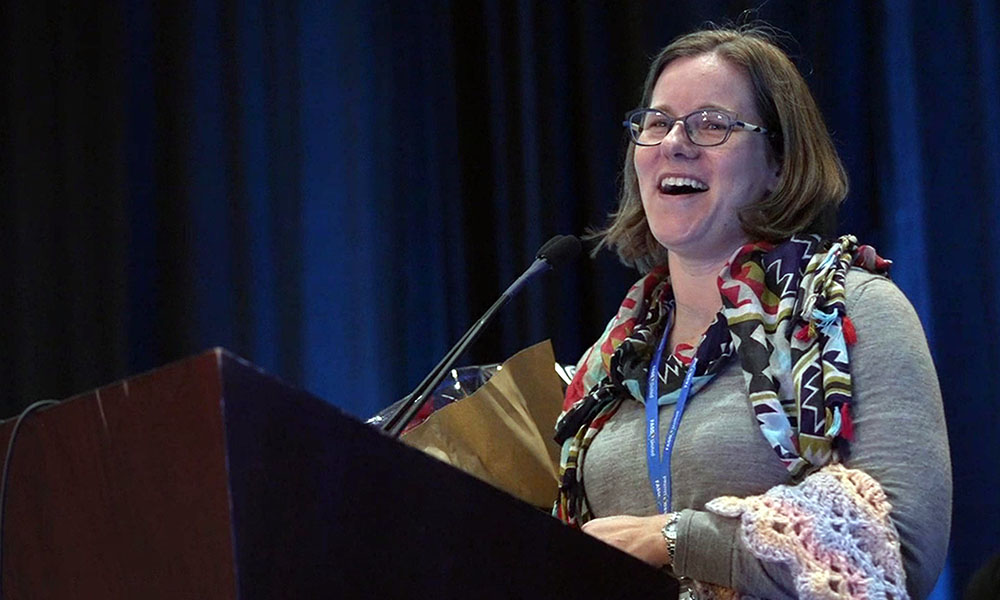 Christie Petrenko smiles while standing at a podium.