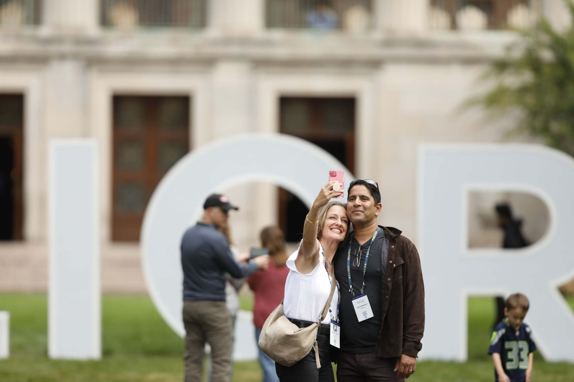 A couple poses for a selfie in front of the giant letters spelling out "Meliora."