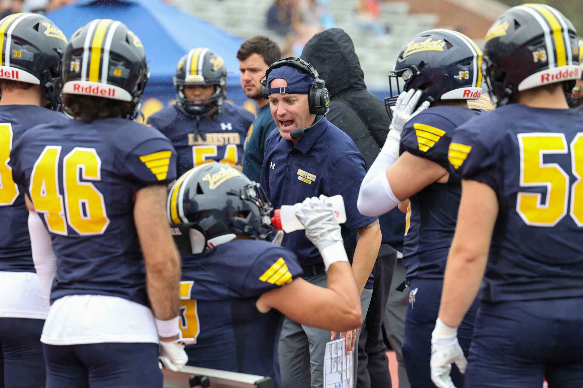 University of Rochester Yellowjackets football team strategizes on the sidelines.