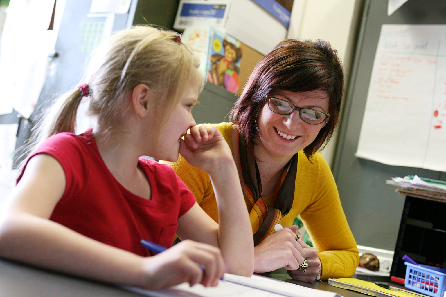 A teacher and a child working together at a desk.