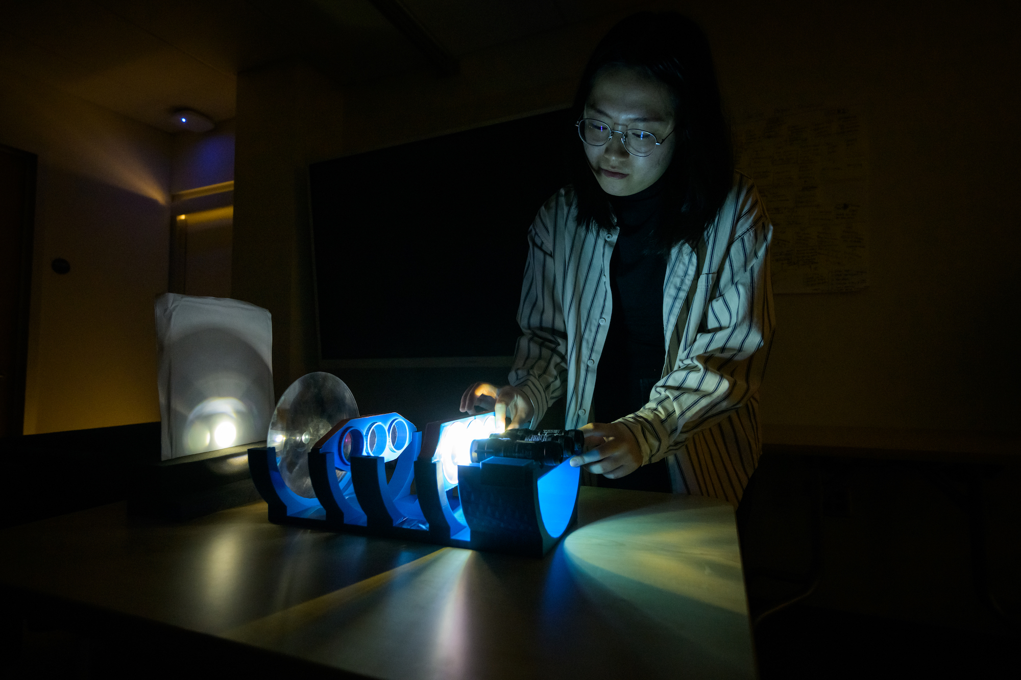 Research Assistant Yi Zhang adjusts a 3D-printed optical device 