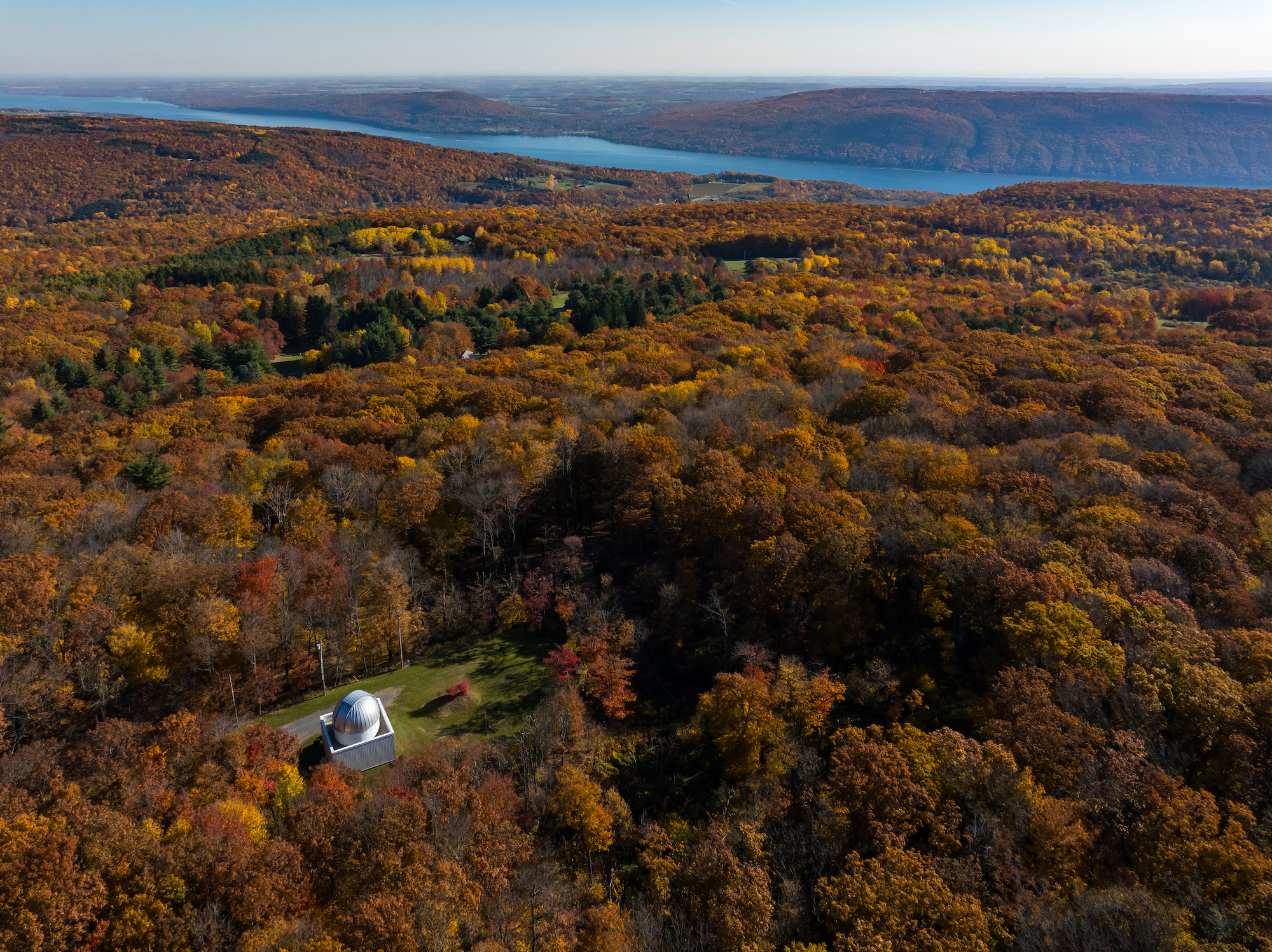 Drone shot of fall foliage surrounding the domed roof of the C E Kenneth Mees Observatory