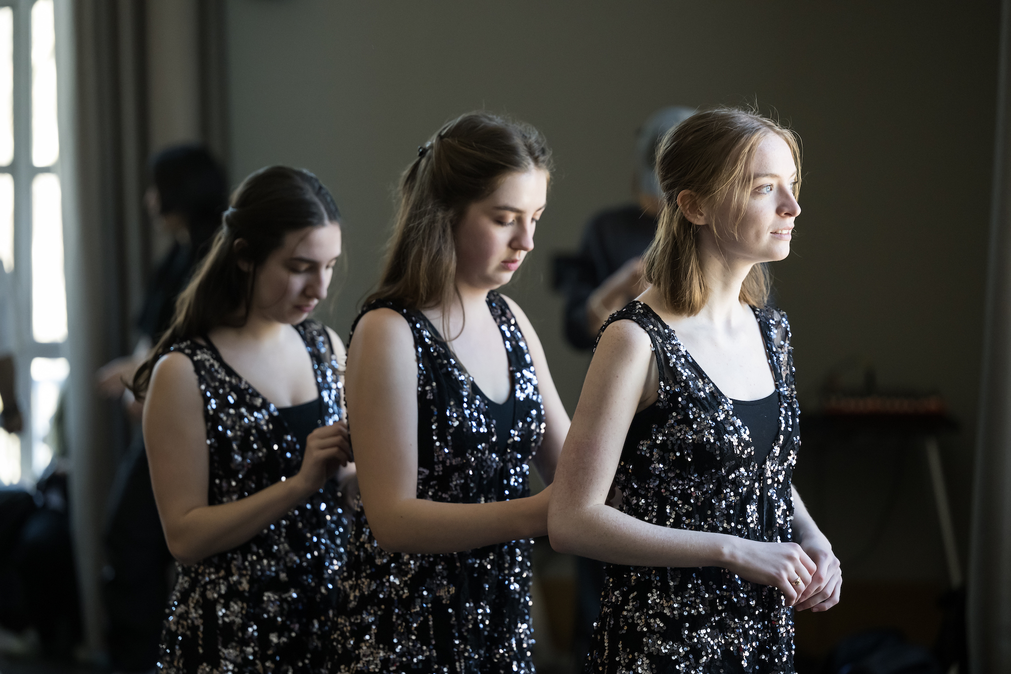 three celtic dancers in sequined costumes wait backstage to go on for a performance 
