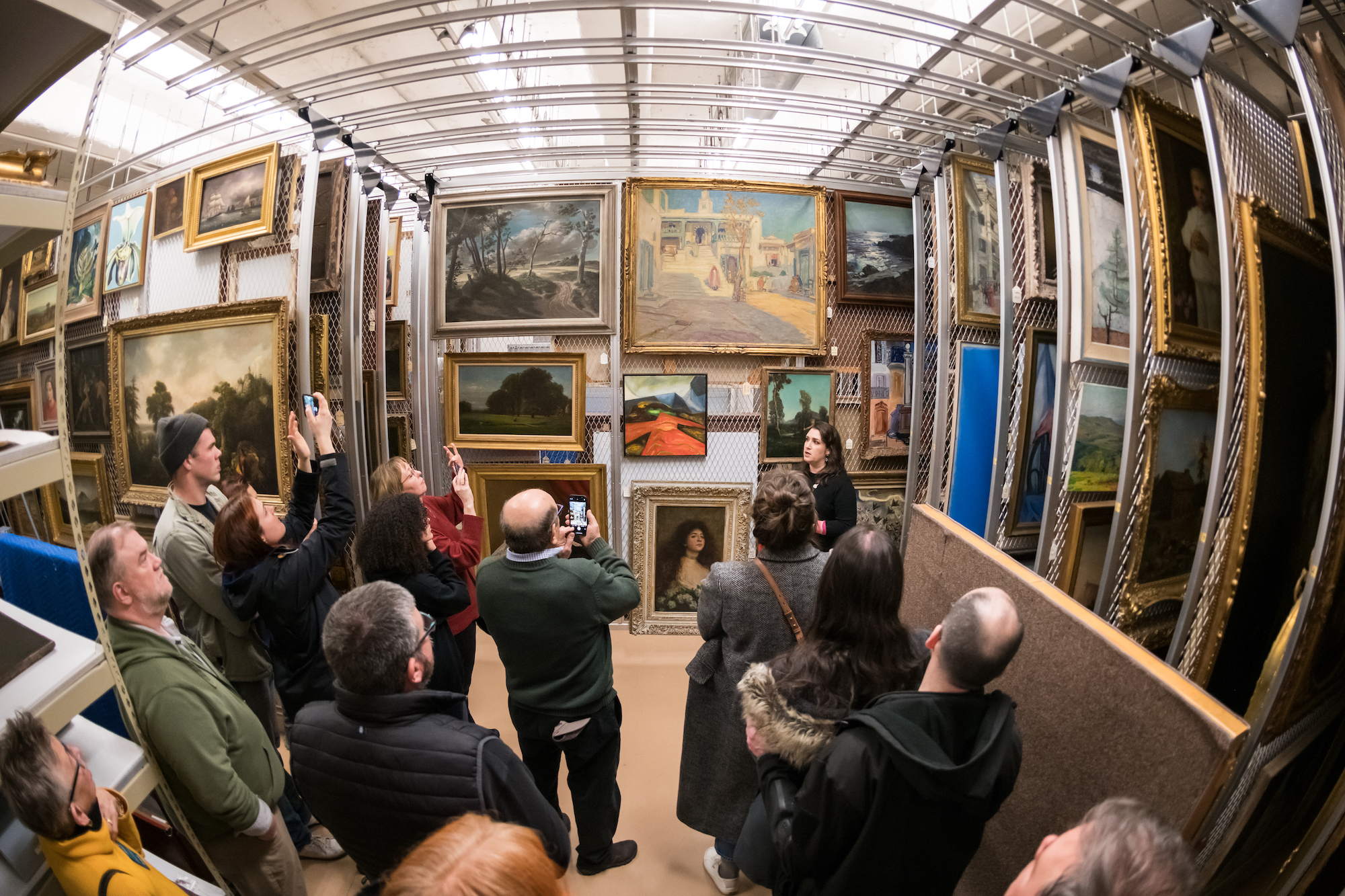 Lauren Tagliaferro, curatorial assistant at the Memorial Art Gallery, speaks to visitors in the painting storage room during a tour of the museum’s art storage area.