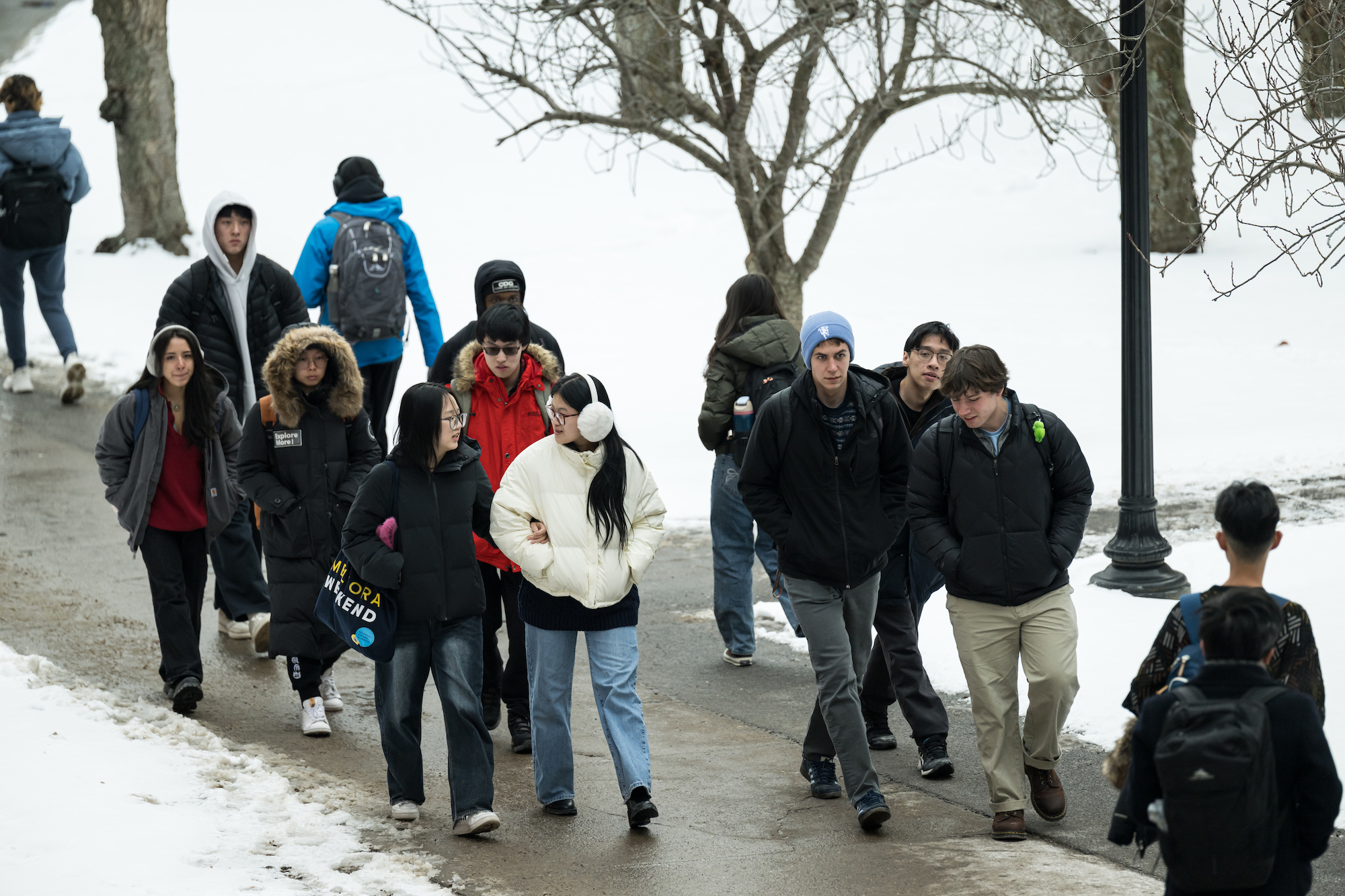 University of Rochester students in outdoor clothing walk through a snowy campus.