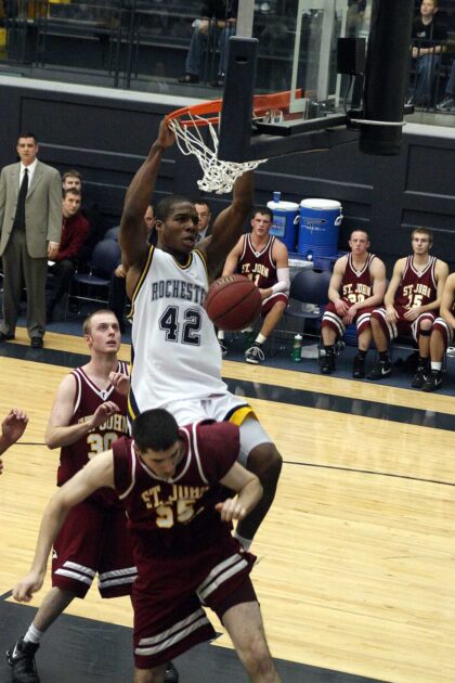 Jon Onyiriuka dunking a basketball in a college game against another team.
