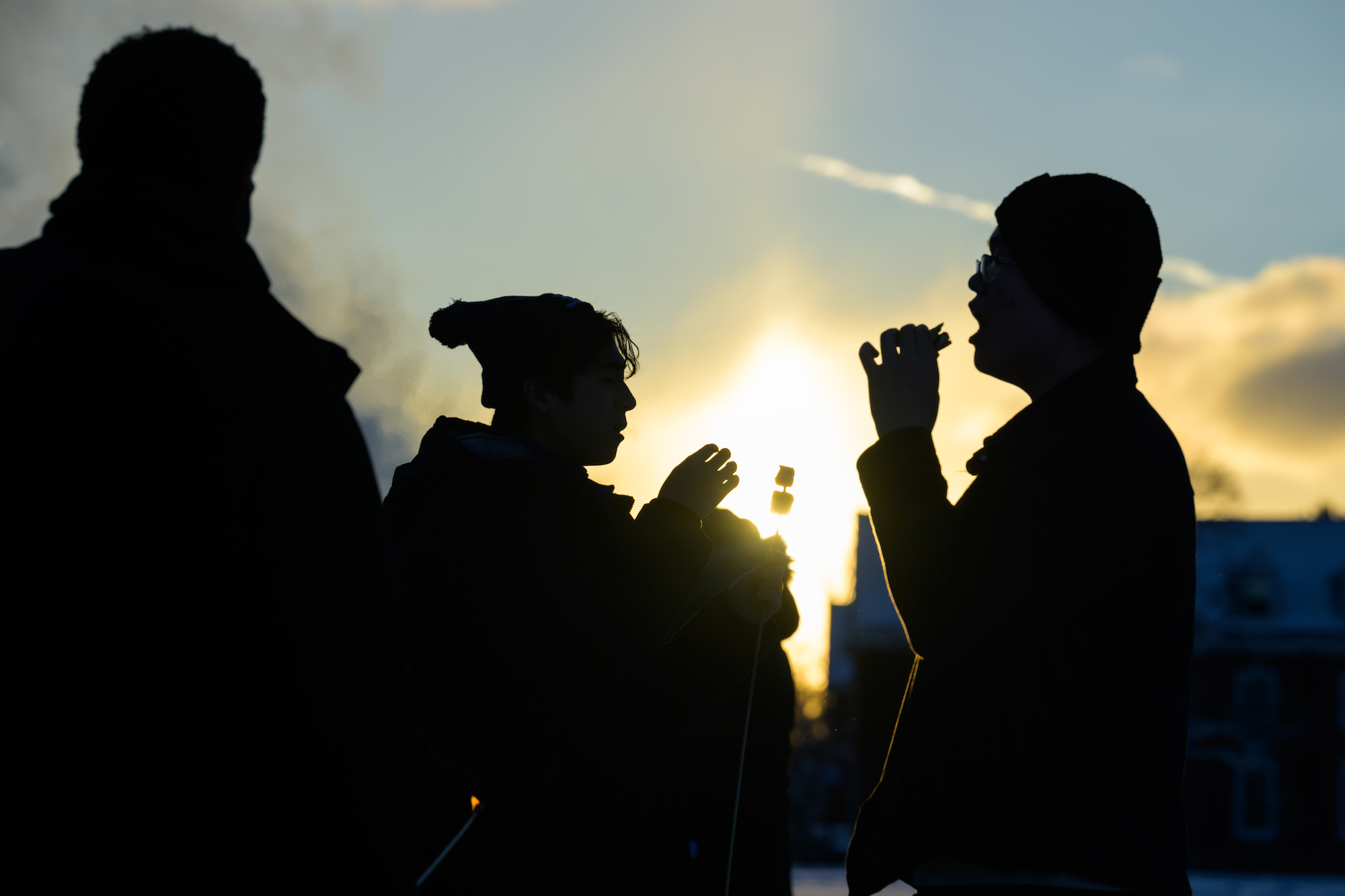 Shadows of three students eating s'mores. 