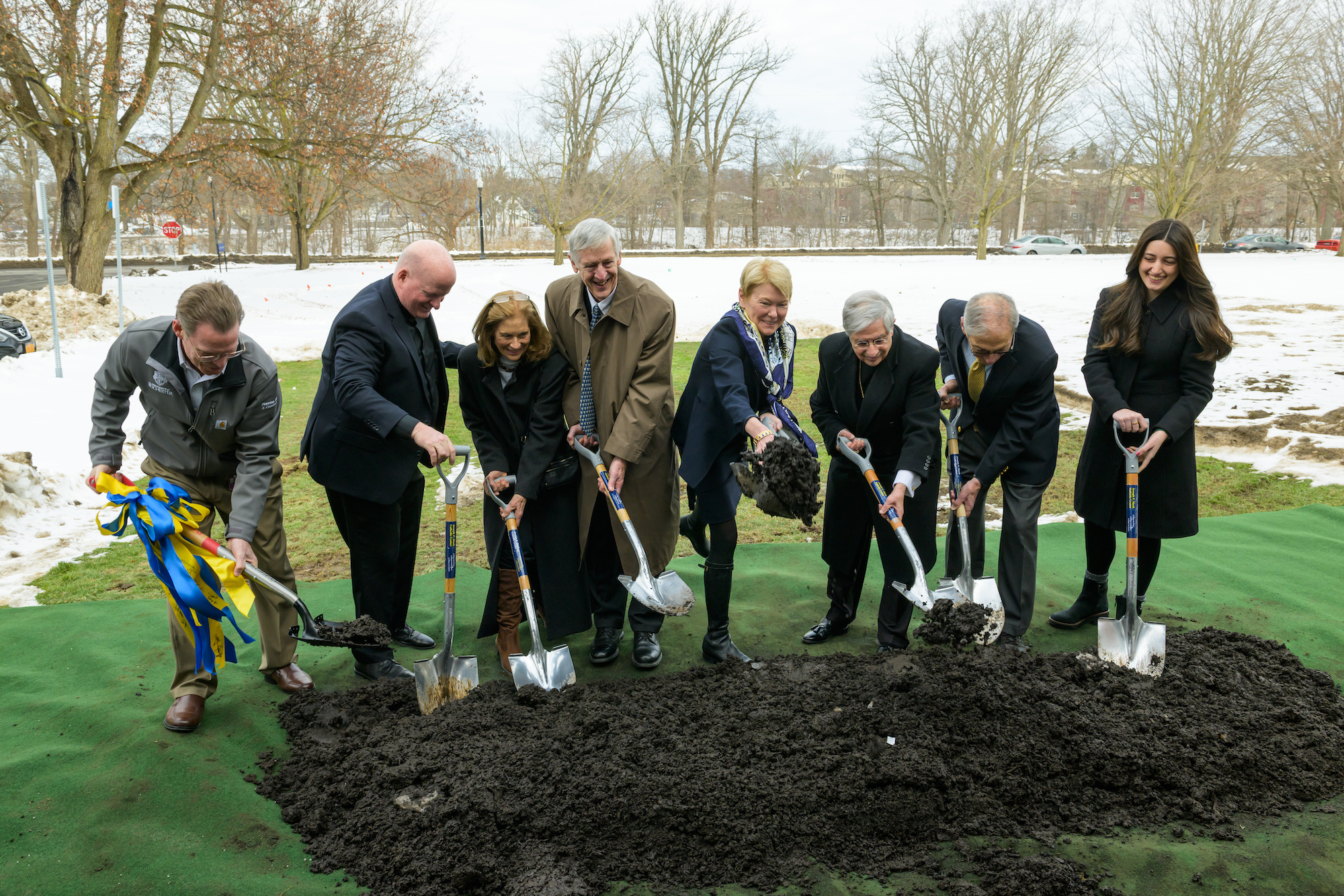 Eight people participate in a groundbreaking ceremony. 