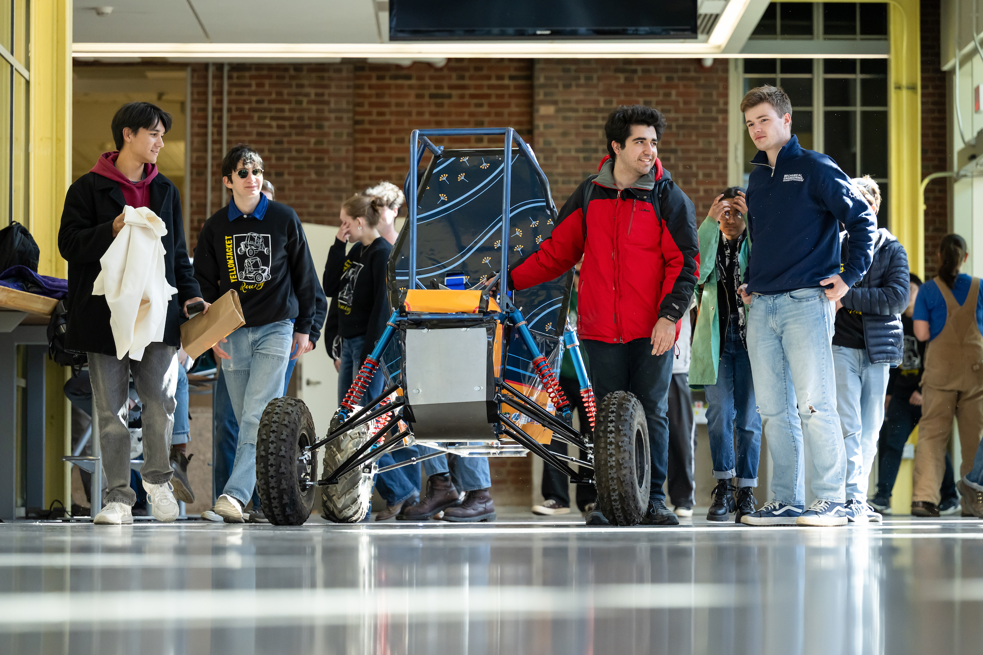 A group of students wheels out a single-seater off-road vehicle.