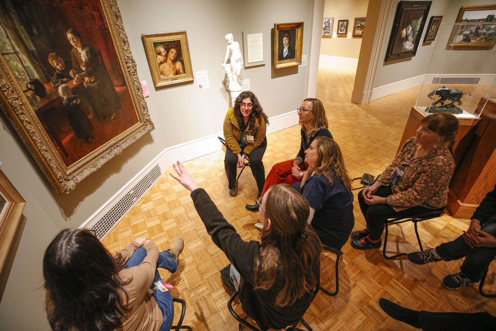A small group with facilitator observes art at the Memorial Art Gallery.