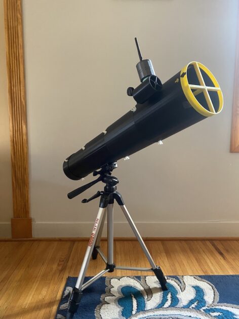 A telescope standing inside a room.