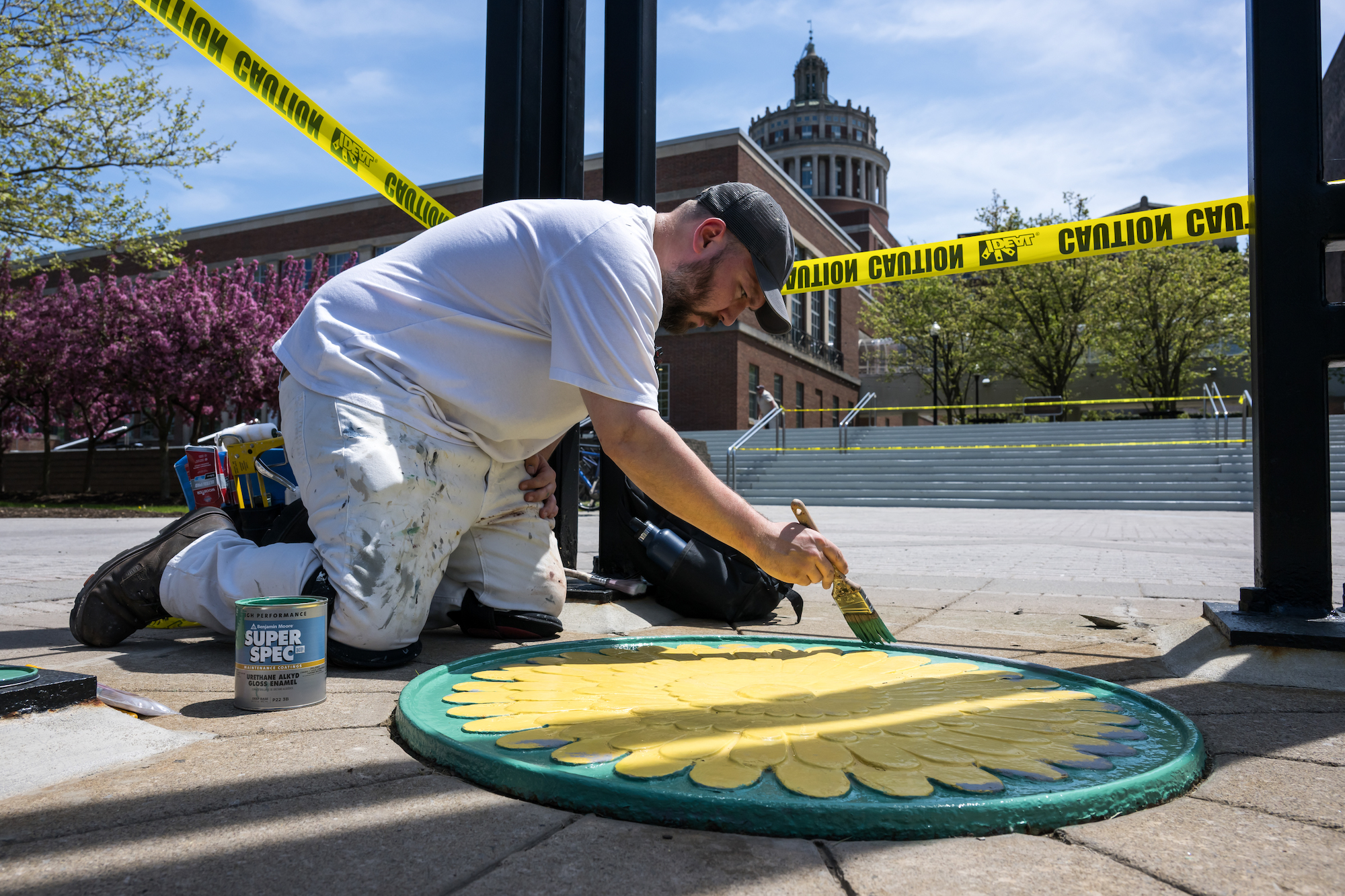 A man applies a biannual coat of paint to the dandelion roundel. 
