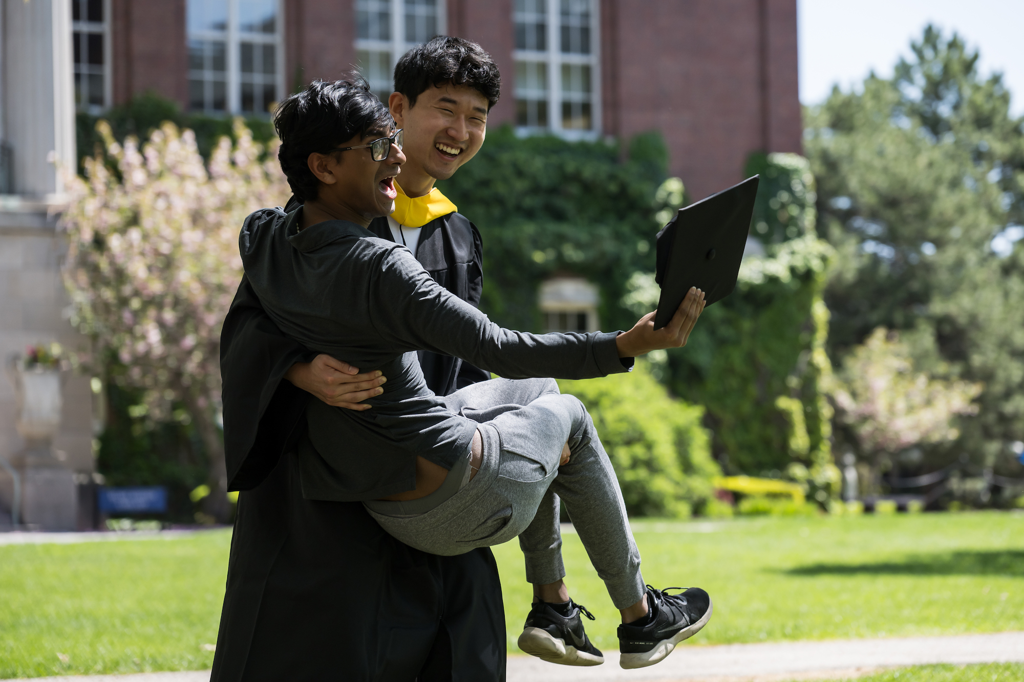 One student carrying another student in celebration. 