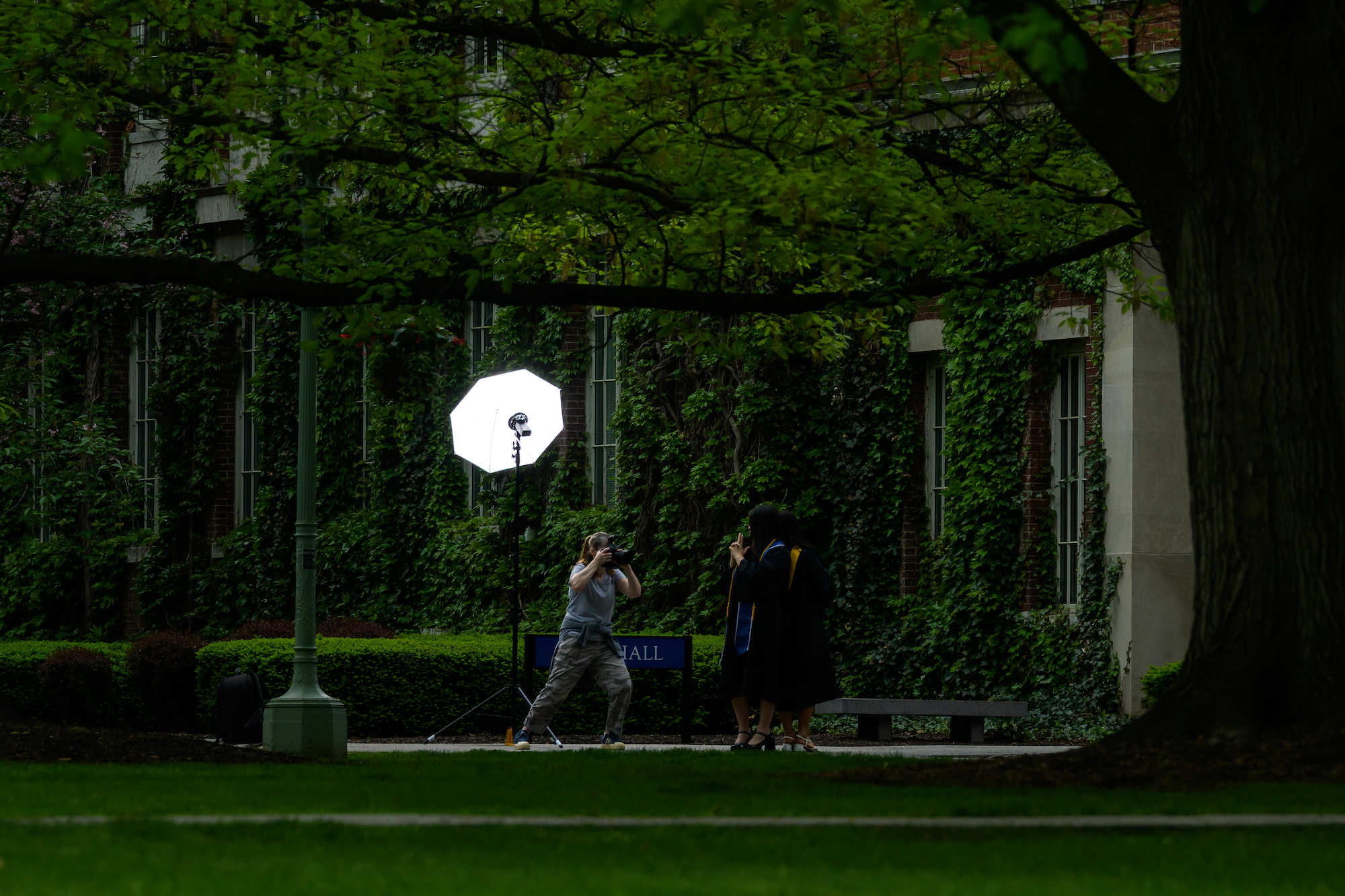 A photographer’s light flashes as graduates pose for photos. 