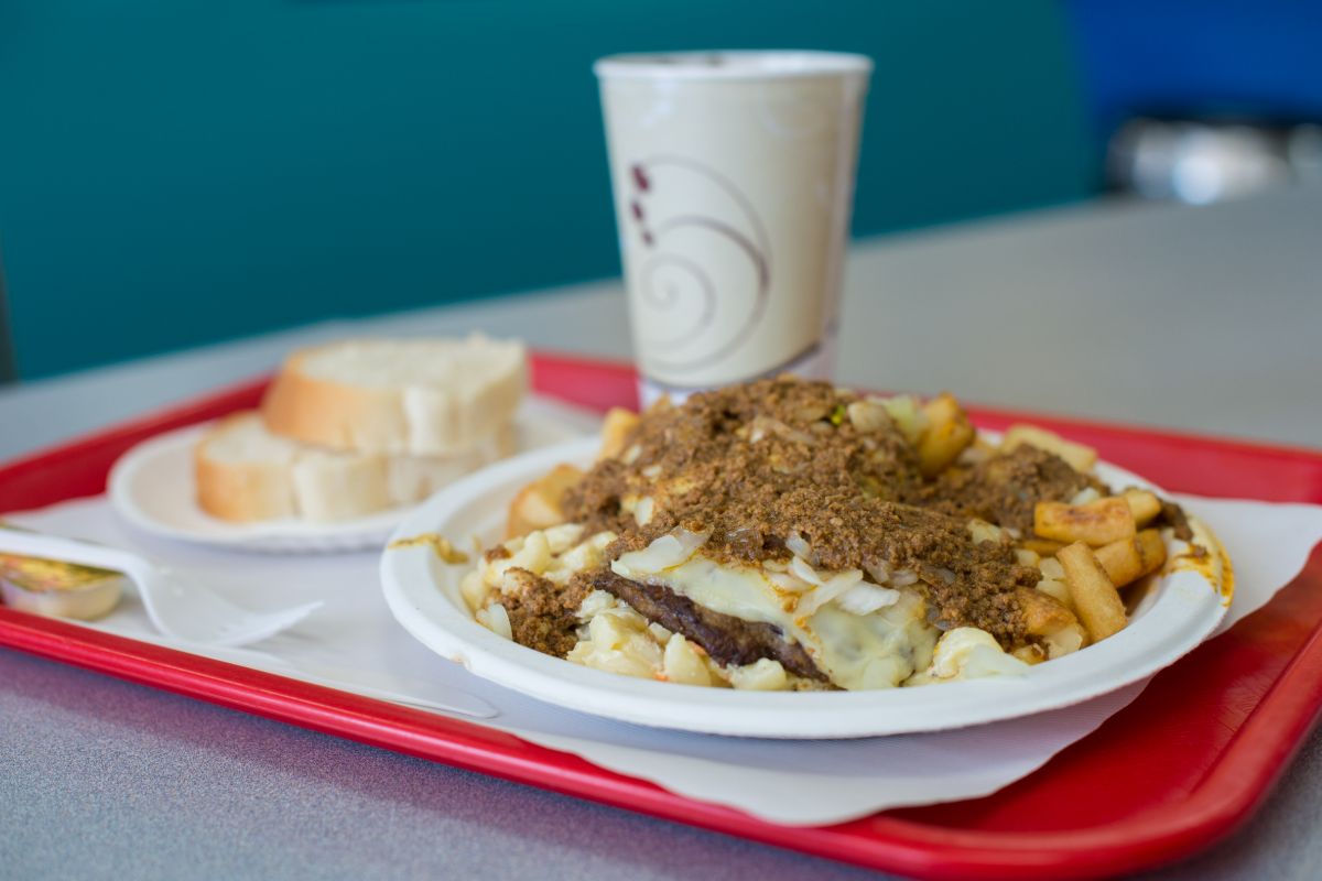 A red tray holds a Rochester garbage plate, featuring a plate of food and a drink.
