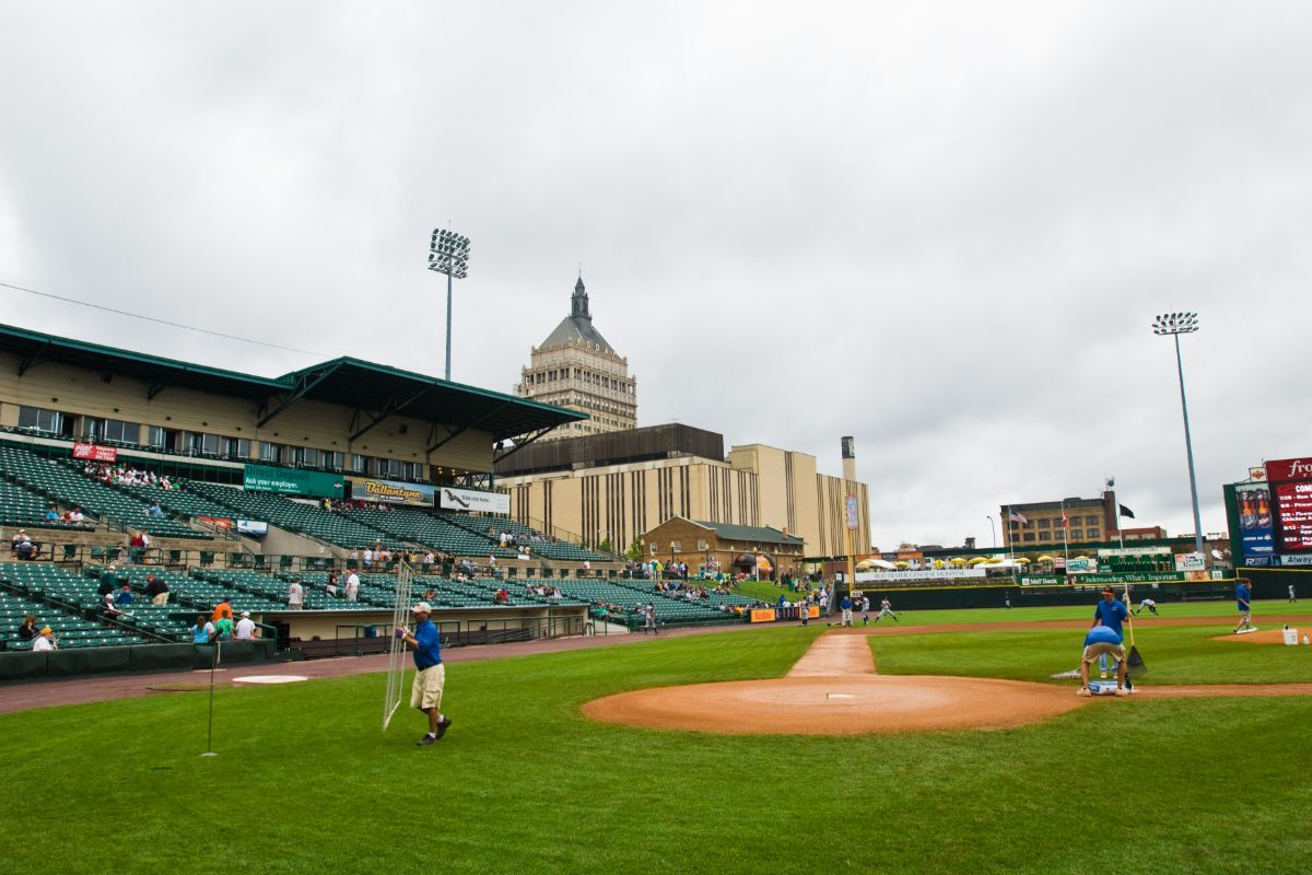 A baseball field at Rochester Red Wings stadium with players in action and a building visible in the background.