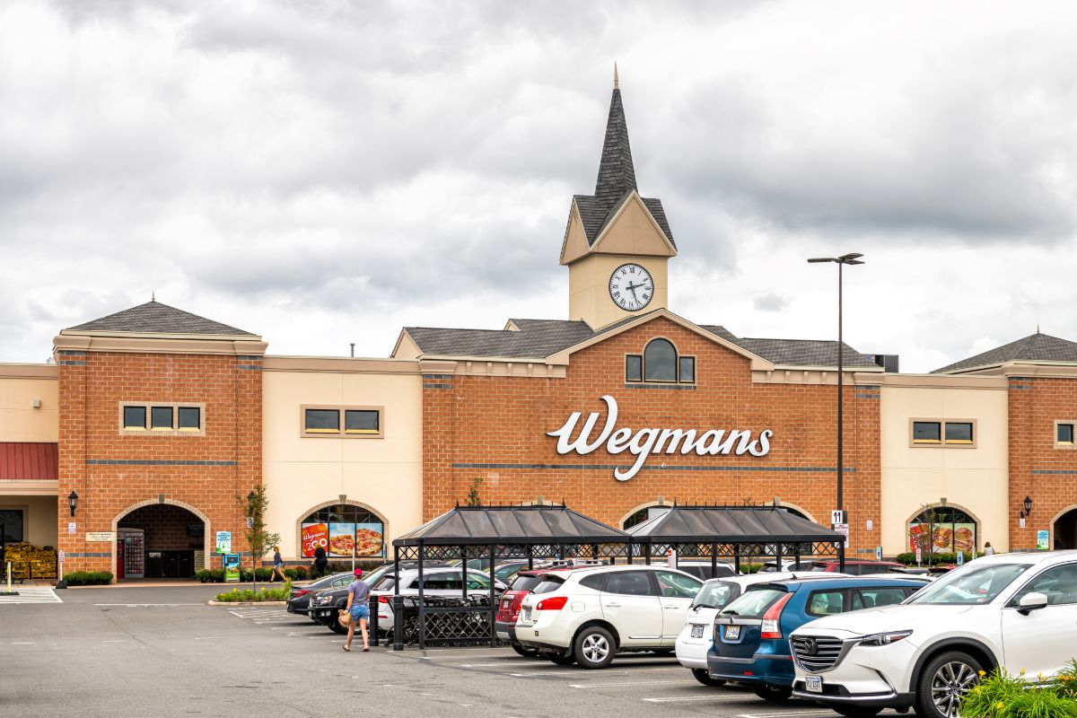 A Wegmans store with several cars parked in front, showcasing the store's entrance and surrounding area.