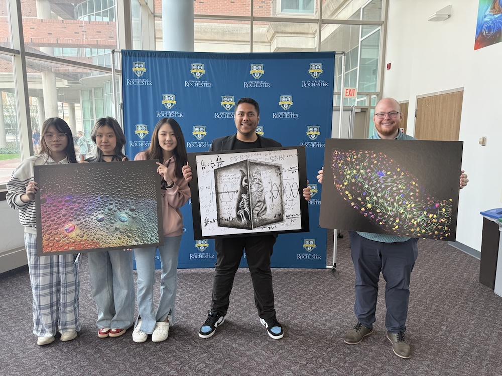 five students hold up three winning pieces of art they created.
