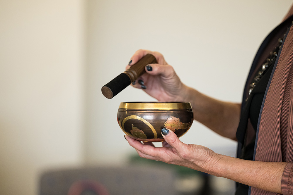 Close-up of an instructor holding a bowl and mallet during a mindfulness session.
