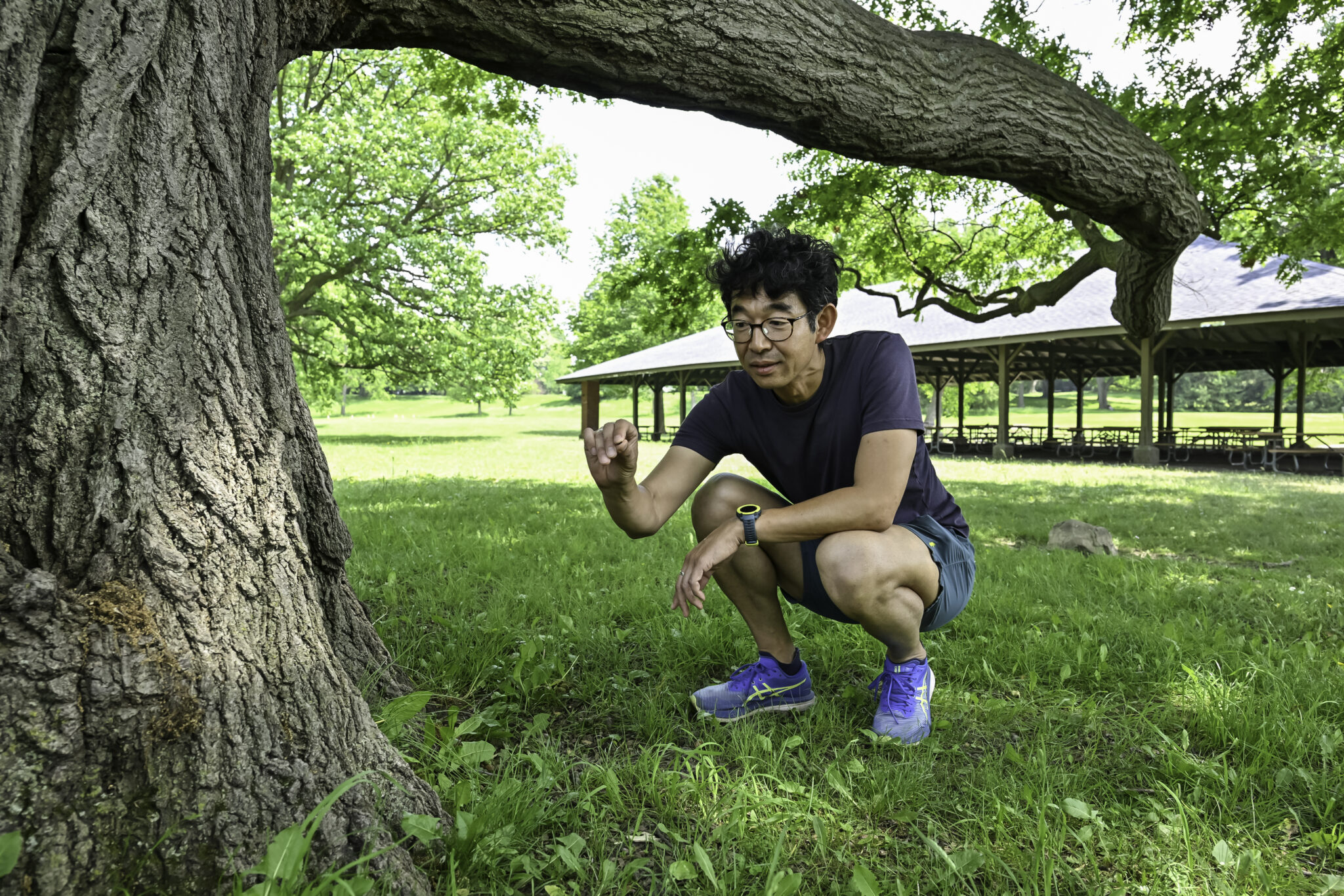 Takao Sasaki kneeling on the ground to collect ants in Genesee Valley Park.