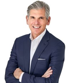 Portrait of a man with a dark suit jacket crossing his arms.