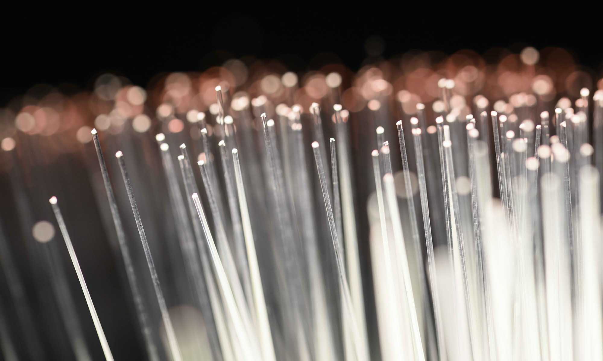 Individual cables of fiber optics lit up white with red at the tips.