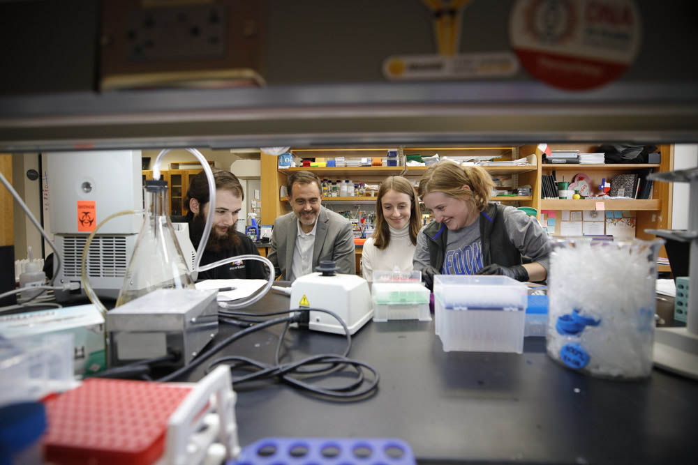 Eric Wagner and three of the members of his lab seen through the shelving in the space.
