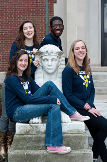 four students sitting near a statue