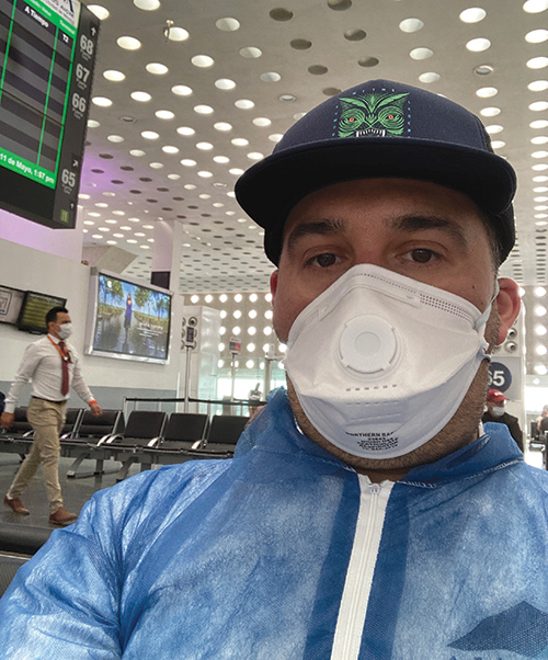 person sitting in an empty airport wearing a mask.