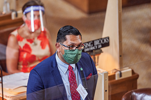 man in a surgical mask standing at a podium.