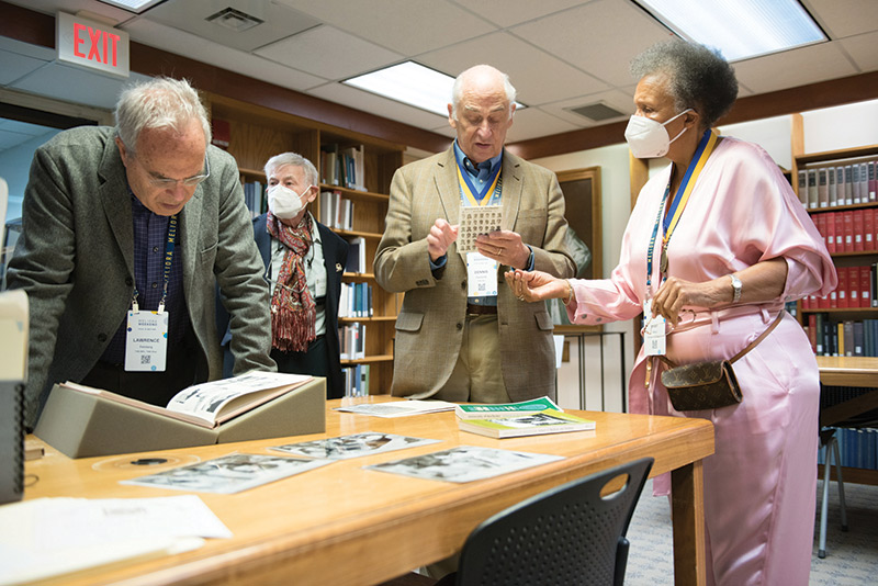 photo of University of Rochester medical school alumni looking through memoribilia set up on a table in a campus library