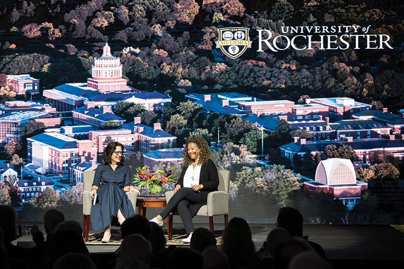 photo University of Rochester dean having a conversation with Michele Norris of the Race Card Project on a stage with a campus background behind them
