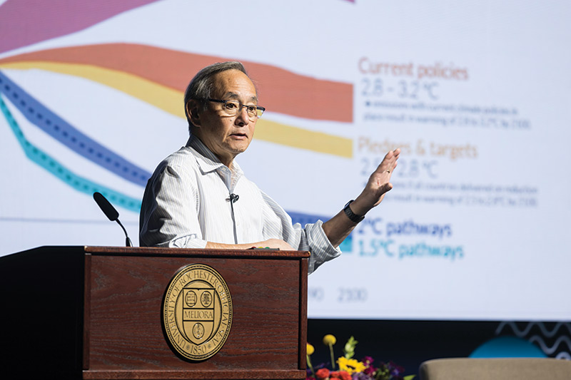 photo University of Rochester alumnus and Nobel laureate Steven Chu gesturing in front of chart on climate change during a campus lecture