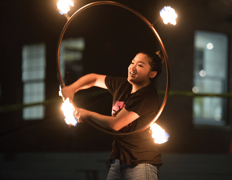 photo of University of Rochester student juggler making a circle with a lit torch during an on-campus performance