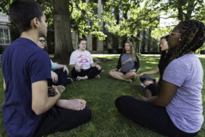 Students sitting in a circle on Eastman Quad meditating. 