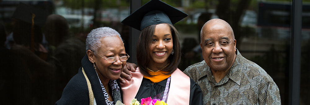 a graduate standing with her parents