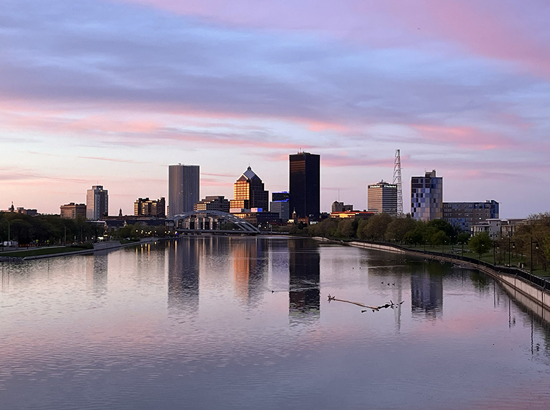 A view of city buildings against a purple and pink sky.