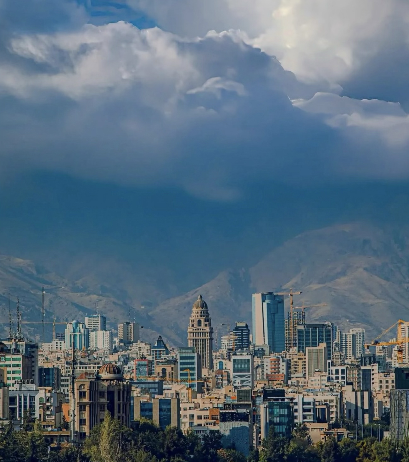 A view of city buildings with mountains and sky in the background.
