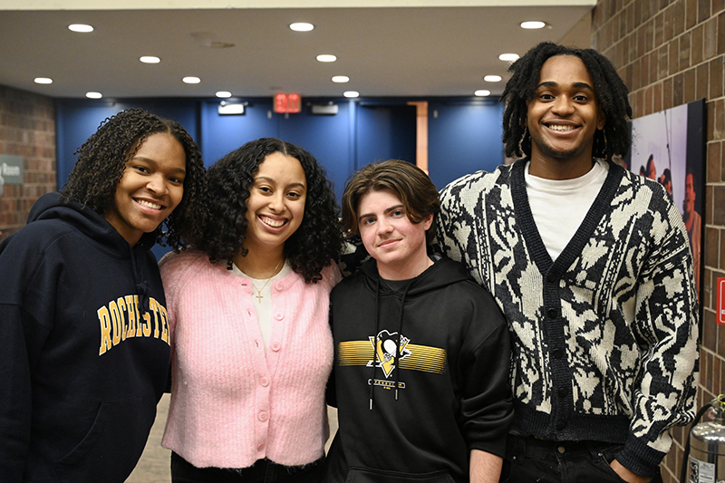 Four people smiling at the camera while standing side by side.