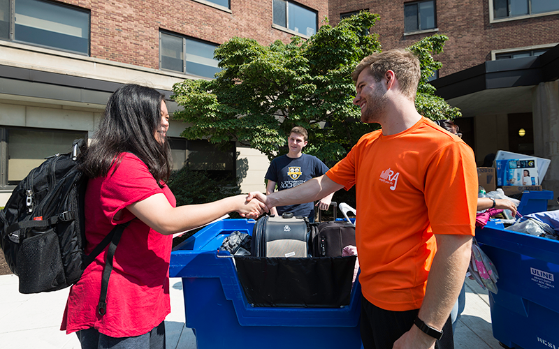 Photo of a Resident Assistant greeting a new student during move-in