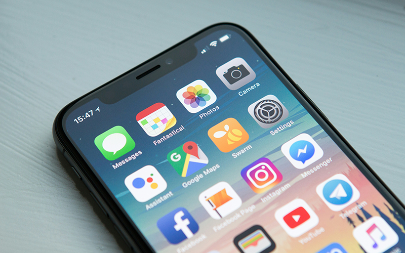 An iPhone laid on a table with the home screen showing