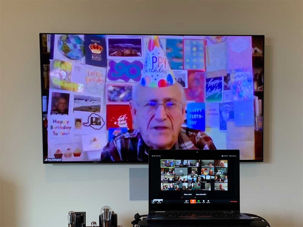 Ray-at-party-with-card-wall-500 Ray Ettington ’51! in a party hat for his birthday on a zoom video call