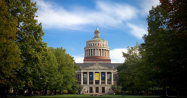 Long view shot of Rhees Library within the middle of a large amount of trees